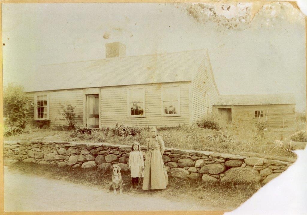 Antique homestead with people outside on a road where sleighs used antique sleigh bells.